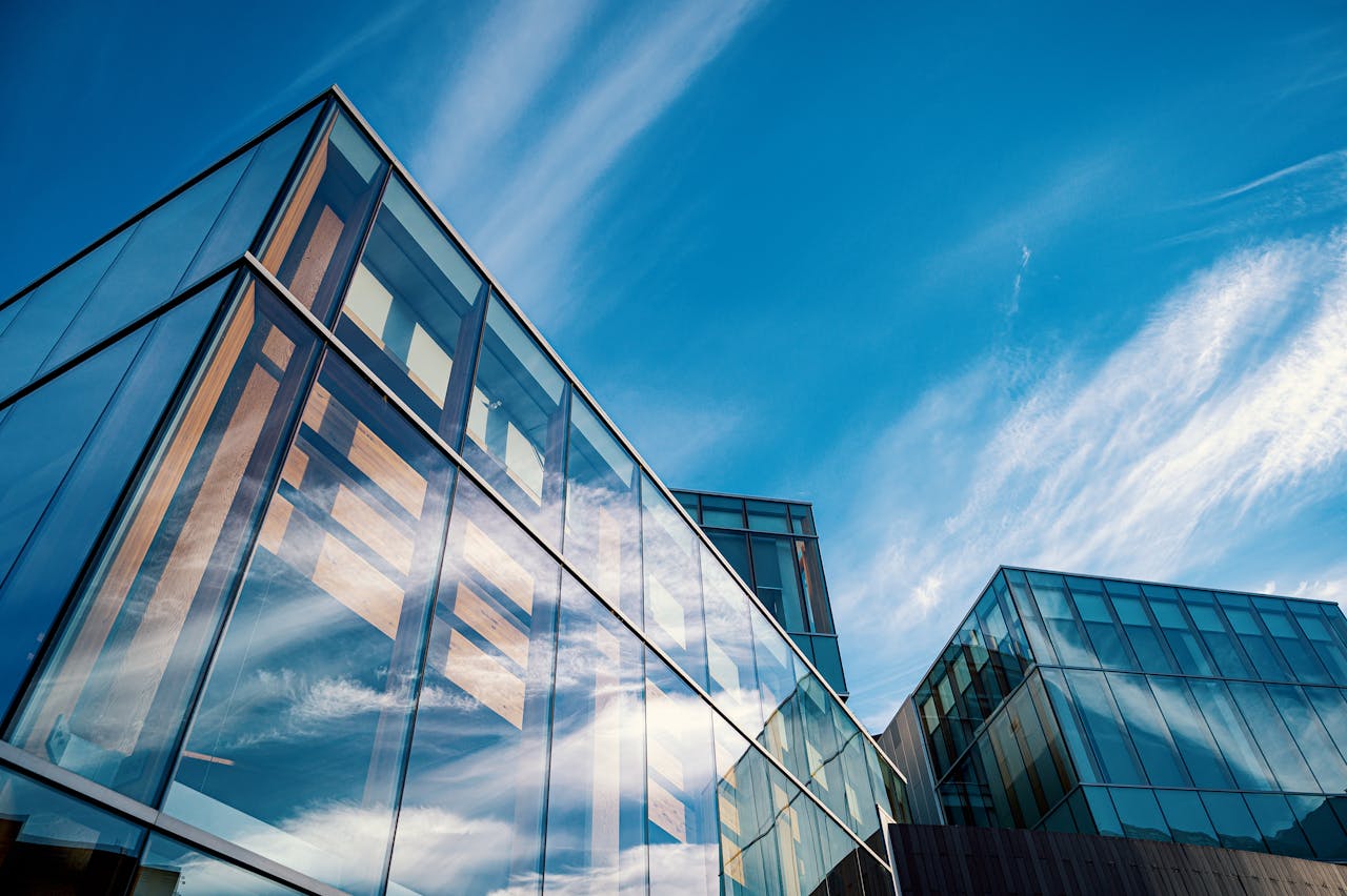 Low angle view of contemporary glass office buildings reflecting a vibrant blue sky.